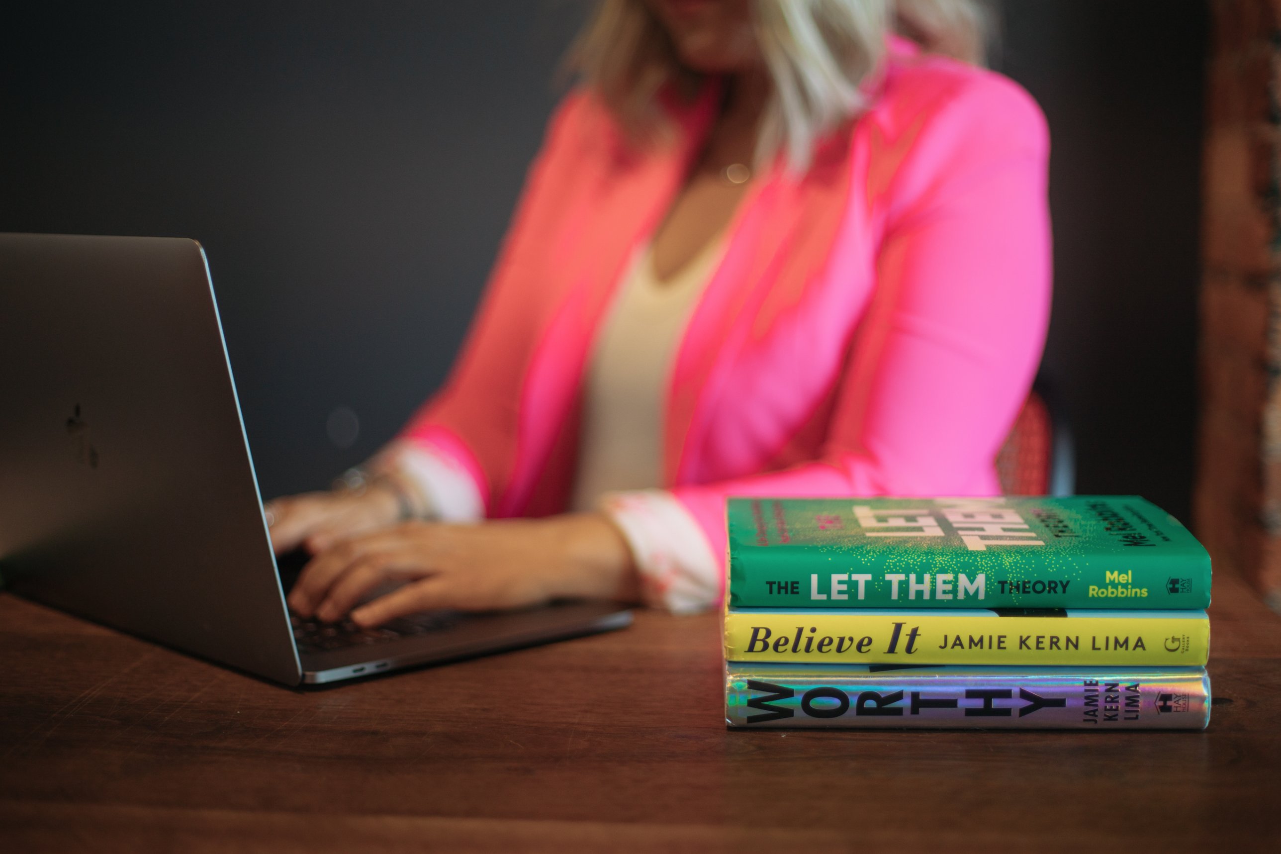Jenn working on her laptop beside a stack of personal development books