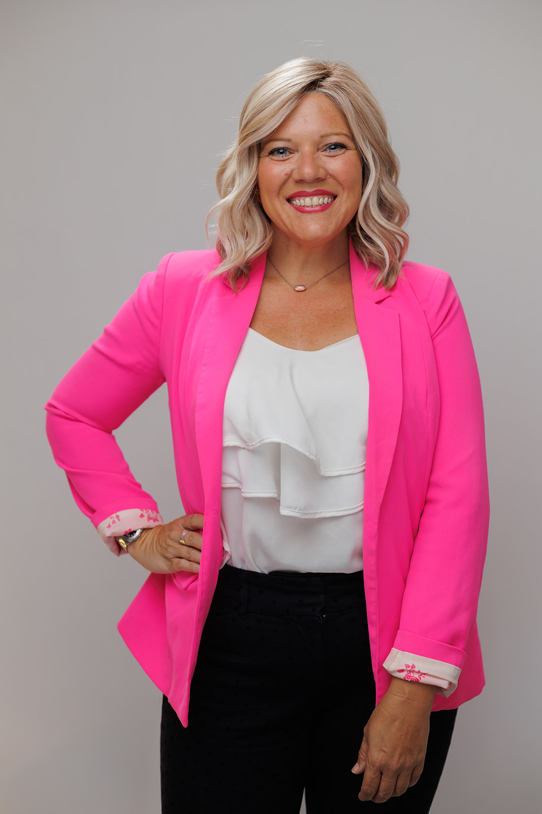 Jenn Gray smiling in a pink blazer